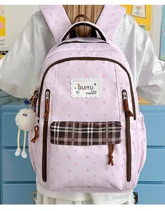 Detail of a pink star-patterned student backpack with a plaid front pocket and plush charm