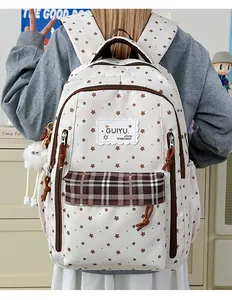 Detailed view of a white backpack with brown star patterns and plaid pocket design.