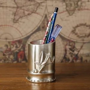 Vista detallada de un portalápices vintage dorado con forma de bambú y hojas en relieve