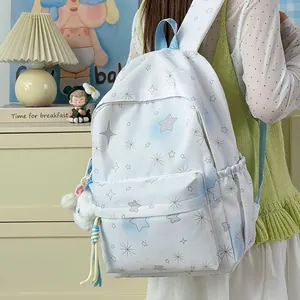 Ein stilvoller weißer Rucksack mit Sternmuster für Mädchen mit süßem Plüsch-Charm-Accessoire