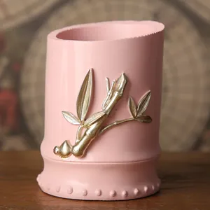 Primer plano de un portalápices rosa minimalista con un relieve de bambú plateado