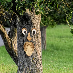 Vista detallada de los adornos de cara de árbol de madera en un tronco del jardín