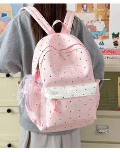 Back view of pink polka dot backpack with lace bow decoration on female model