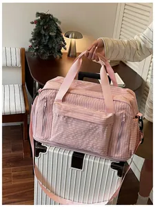 Pink large capacity travel bag with textured fabric placed on a white suitcase