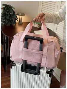 Detail of the pink travel duffel bag featuring a convenient suitcase handle sleeve for travel