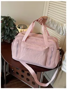 Macro detail of pink quilted travel bag showing textured fabric, zippers, and logo