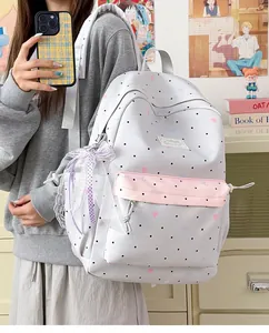 Lifestyle view of a cute grey polka dot backpack with lace bow and pink pocket
