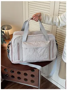Hand carrying a stylish large capacity striped travel duffel bag with adjustable strap
