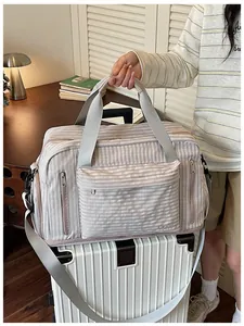 Close-up of a large capacity striped travel bag resting on top of a white suitcase
