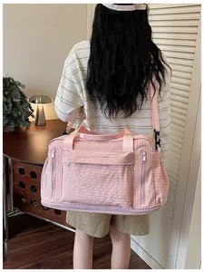 Large pink travel duffel bag with multi-functional pockets shown on a model's back