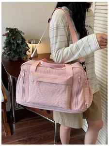 Model carrying large pink travel bag with shoulder strap and side zipper pockets.