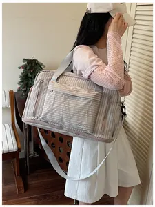 Detailed close-up of a large capacity striped travel duffel bag worn by a model indoors