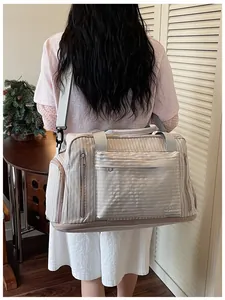 Model carrying a large beige striped travel bag with shoulder strap for gym and trips