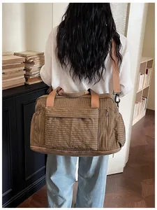 Back view of model carrying a large capacity brown checkered travel bag in study