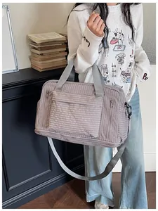Lifestyle shot of a large mauve checkered travel duffel bag being carried by a model.