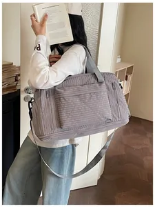 Large capacity gray travel duffel bag with quilted pattern shown on model's shoulder