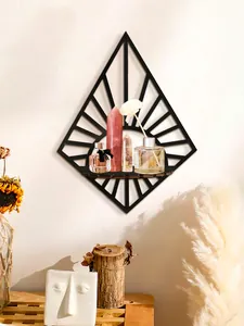 Modern black diamond-shaped wall shelf used as a display stand for crystals and perfume.