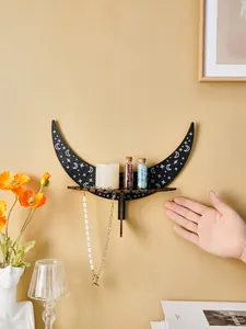 Detailed view of a black wooden crescent moon shelf with star patterns on a yellow wall