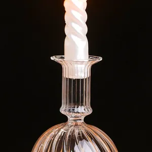 Detail van een elegante geribbelde glazen kandelaar met een witte gedraaide kaars