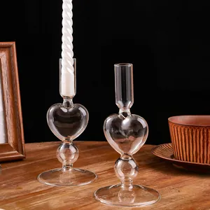 Eleganti portacandele in vetro trasparente a forma di cuore su tavolo in legno