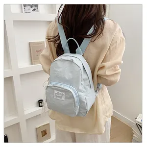 Back view of a model wearing a simple light blue casual travel backpack for daily use.