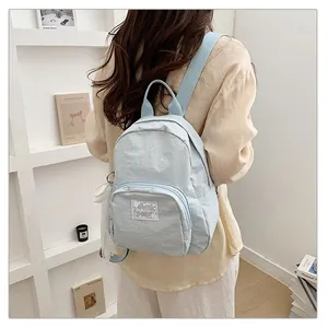 Rear view of a model wearing a light blue minimalist nylon backpack for school and travel