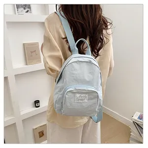 Back view of a student wearing a light blue minimalist casual fabric backpack