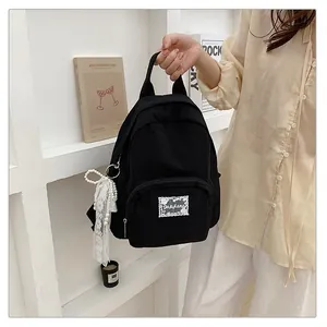 Detail view of a black minimalist student backpack with lace and pearl accessory