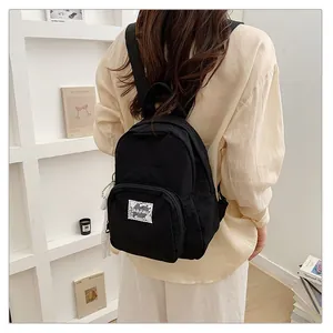 Detailed view of the black minimalist student backpack worn by a model in a cozy room.