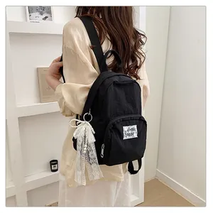 Minimalist black student backpack featuring a stylish decorative white lace bow