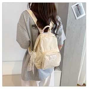 Close-up detail of a cream minimalist backpack with a lace pearl charm accessory