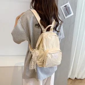 Minimalist cream nylon backpack with lace keychain accessory