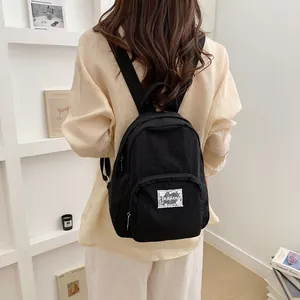 Minimalist solid black casual student backpack shown from a back view on a model