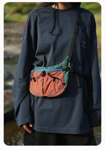 Modell mit einer farbenfrohen Outdoor-Umhängetasche im Sonnenuntergang-Design.