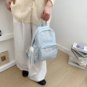 Light blue minimalist backpack for students with lace pearl charm in lifestyle setting