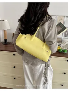 Detalle de un bolso baguette vintage amarillo brillante llevado como bolso de hombro