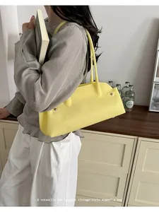 Elegante bolso baguette amarillo combinado con blusa gris y pantalones blancos