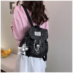 Stylish black backpack with white star pattern worn by a model in a casual setting.
