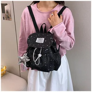 Detailed view of the black mini backpack with star pattern worn by a model in a stylish outfit