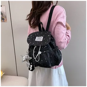 Back view of a black star pattern mini backpack worn by a model in a casual setting