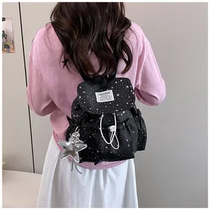 Close-up back view of a black lightweight mini backpack with star pattern worn by a model