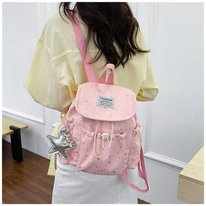 Back view of a pink star-patterned mini backpack worn by a model in a trendy setting