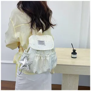 Lifestyle detail of a white star pattern mini backpack being worn by a female model