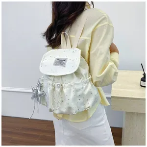 Lifestyle view of a white mini backpack with star patterns worn over the shoulder
