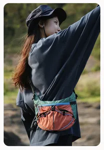 Stilvolle Outdoor-Tasche in Blockfarben, getragen von einem Model in der Natur
