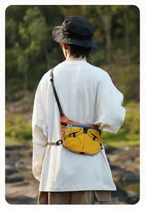 Detailansicht einer gelb-orangefarbenen Crossbody-Tasche im Outdoor-Design getragen