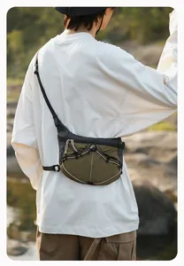 Outdoor-Lifestyle-Ansicht einer olivgrünen farbblockierten Umhängetasche an einem Modell