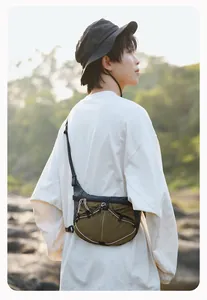 Asiatischer Mann trägt olivgrüne und schwarz karierte Crossbody-Tasche im Freien