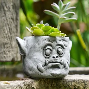 Gros plan d'un pot de fleurs créatif en résine avec visage de monstre pour succulentes