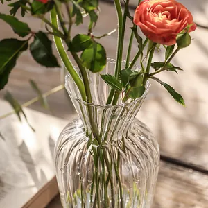 Detail einer Vintage Glasvase mit Rippenmuster und orangefarbenen Rosen auf Holztisch